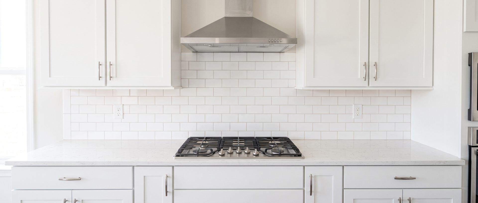 A deep-cleaned kitchen: degreased range hood, scrubbed grout between the tiles, and a clear counter