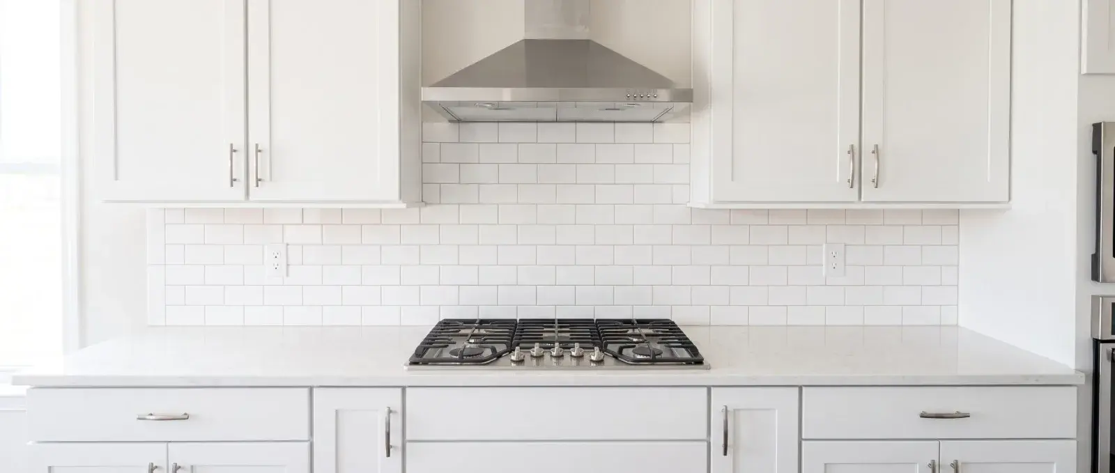 A deep-cleaned kitchen: degreased range hood, scrubbed grout between the tiles, and a clear counter