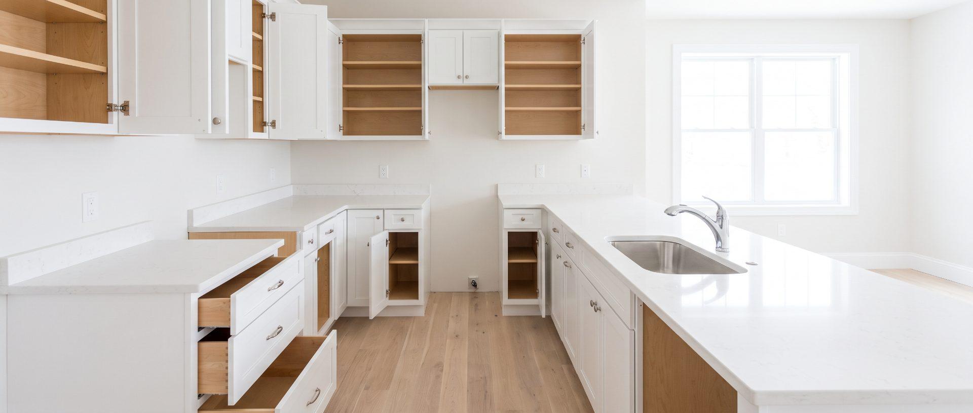 An emptied kitchen after a move-out clean, cabinet doors and drawers open on bare, wiped shelves